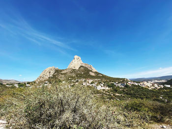 Low angle view of rocky mountain against blue sky