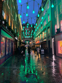 People walking on wet street in city during rainy season