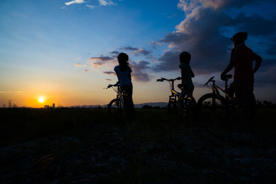 Silhouette people on field against sky during sunset