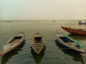 Fishing boats moored in sea against sky