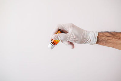 Close-up of hand holding bottle against white background