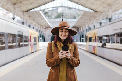 Full length of man using mobile phone while standing on bus