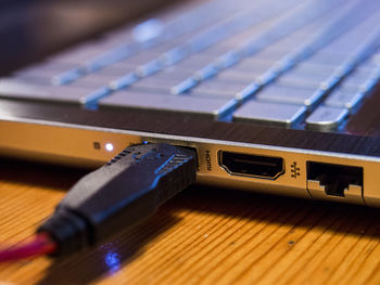 Close-up of usb cable attached to laptop on table