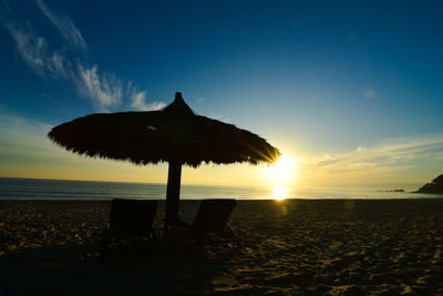 Silhouette structure on beach against sky during sunset