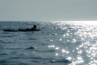 Silhouette man in sea against clear sky