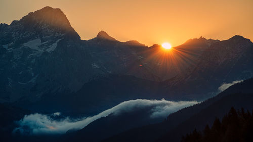 Sun shining through clouds over mountains