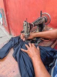 Cropped hand of woman using sewing machine