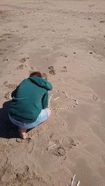 Rear view of man sitting on sand at beach