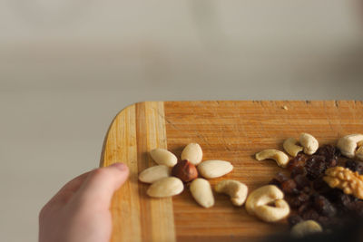 Cropped image of person holding nuts on cutting board