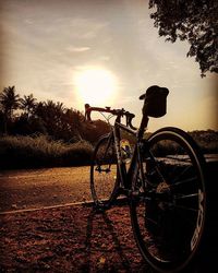 Bicycle parked on road at sunset