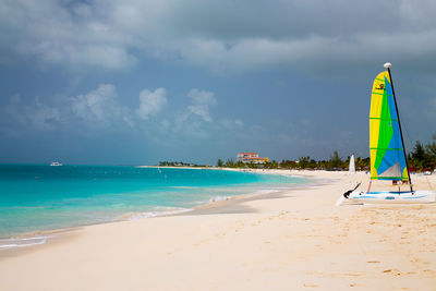 Sailboats moored at beach against sky