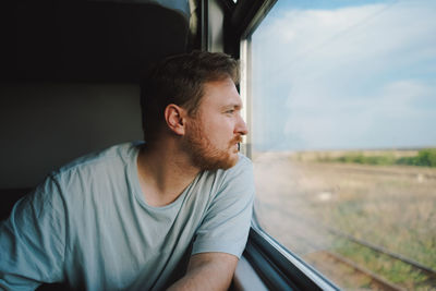 A man in a blue t-shirt while traveling by railway train