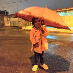 Full length of cute boy standing in rain during rainy season