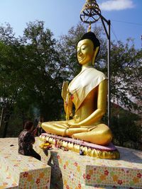 Low angle view of buddha statue against trees