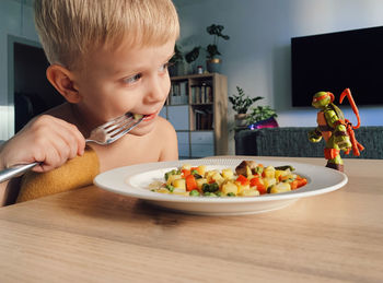 Close-up of boy eating food on table