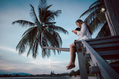 Rear view of woman standing by sea against sky