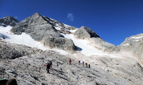 People on snowcapped mountain against blue sky