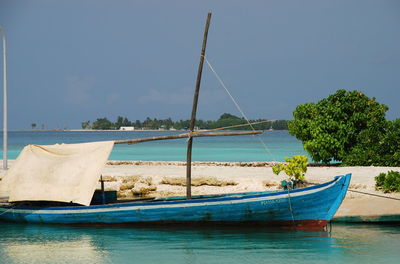 Boats moored in calm blue sea against sky