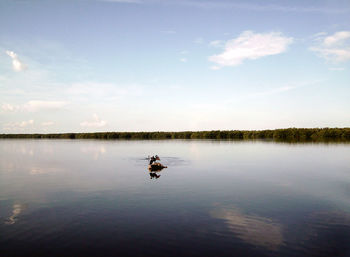 People on boat in lake against sky