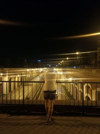 Rear view of man walking on footpath at night