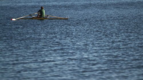 Rear view of man on rowing boat in lake