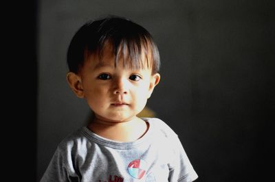 Portrait of cute boy against black background