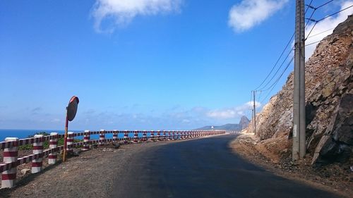 Road by beach against blue sky