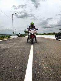 Rear view of man riding motorcycle on road