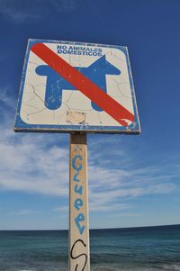 Close-up of road sign by sea against sky