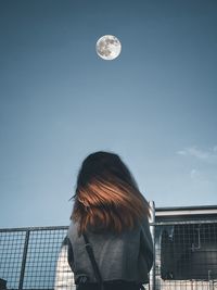 Rear view of woman standing against moon