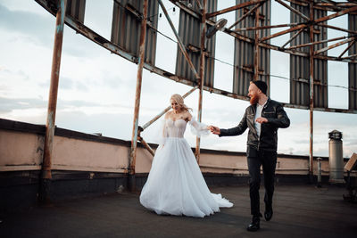 Couple holding hands while running on building terrace