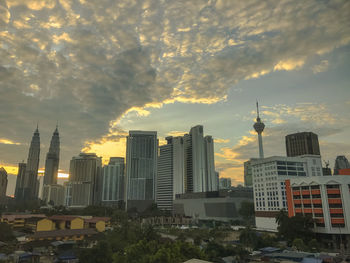 Buildings in city against cloudy sky during sunset