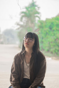 Thoughtful beautiful young woman sitting outdoors