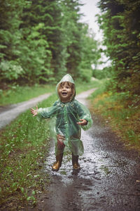 Charming child in a raincoat in the evening forest in denmark