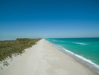 Scenic view of beach against clear blue sky