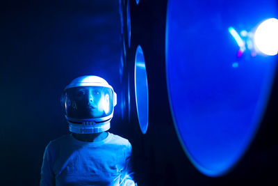 Astronaut wearing space helmet by blue illuminated light