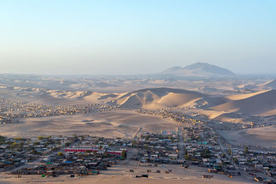 Village in desert against clear sky at huacachina