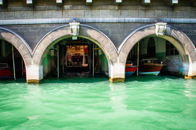 Arch bridge over canal by swimming pool in building