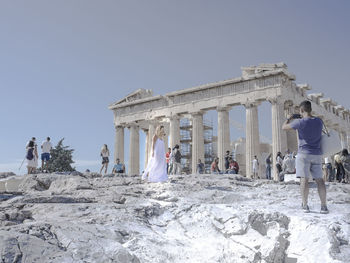 People at historical building against clear sky