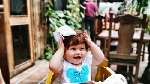 Happy playful girl sitting in chair at sidewalk cafe