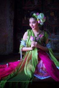 Beautiful bride in traditional clothing sitting on table
