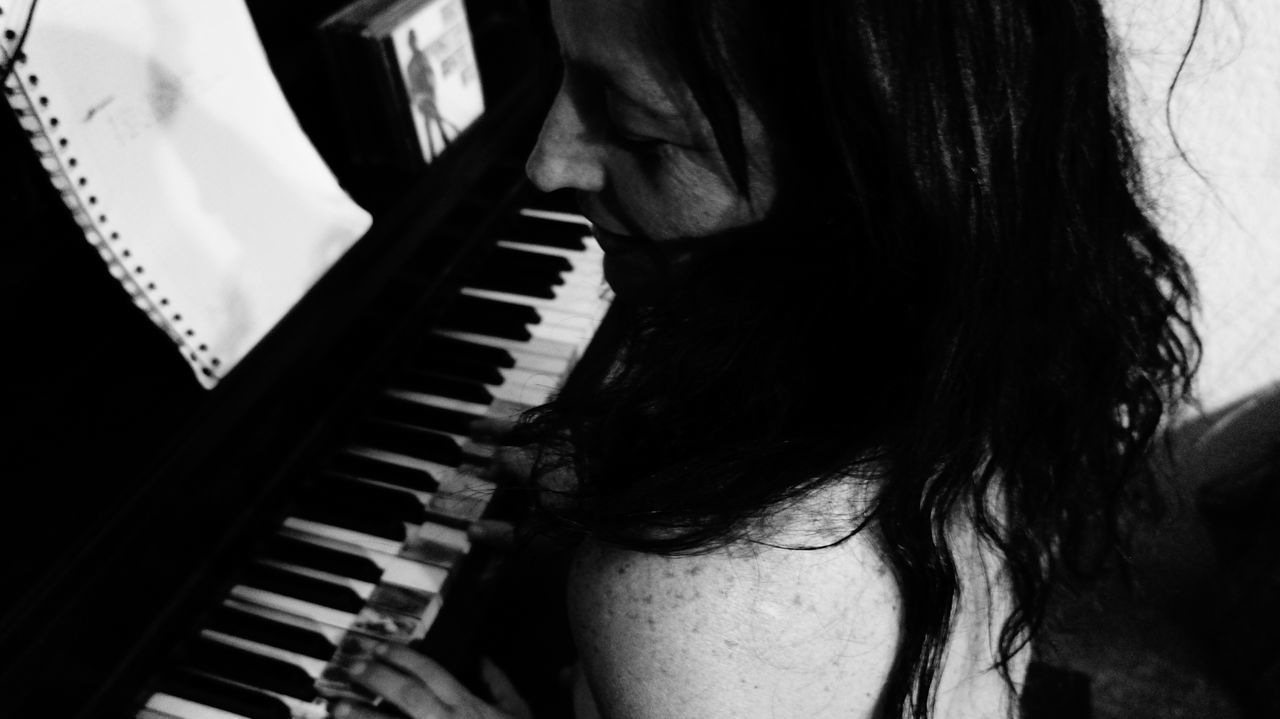 CLOSE-UP OF WOMAN PLAYING WITH PIANO IN BACKGROUND