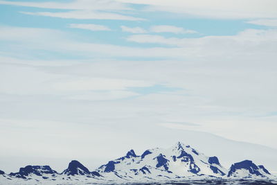 Snowy mountains against cloudy sky