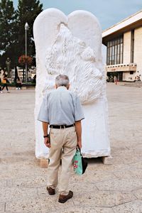 Rear view of woman standing in front of house