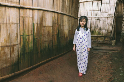 Portrait of young woman standing against wall