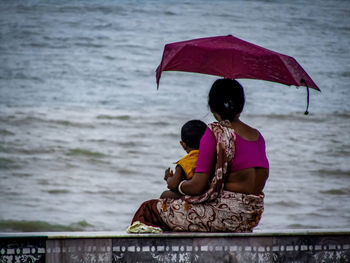 Rear view of couple sitting on sea shore