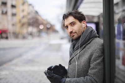 Elegant man with smartphone waiting on bus stop