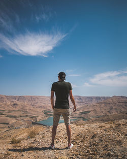 Rear view of man standing on land against sky