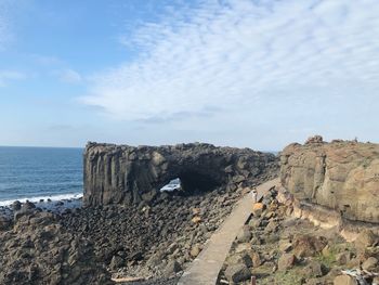 Rock formations on shore against sky