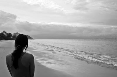 Rear view of woman standing at beach